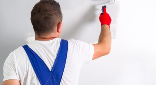 Hombre pintando con rodillo una pared en blanco