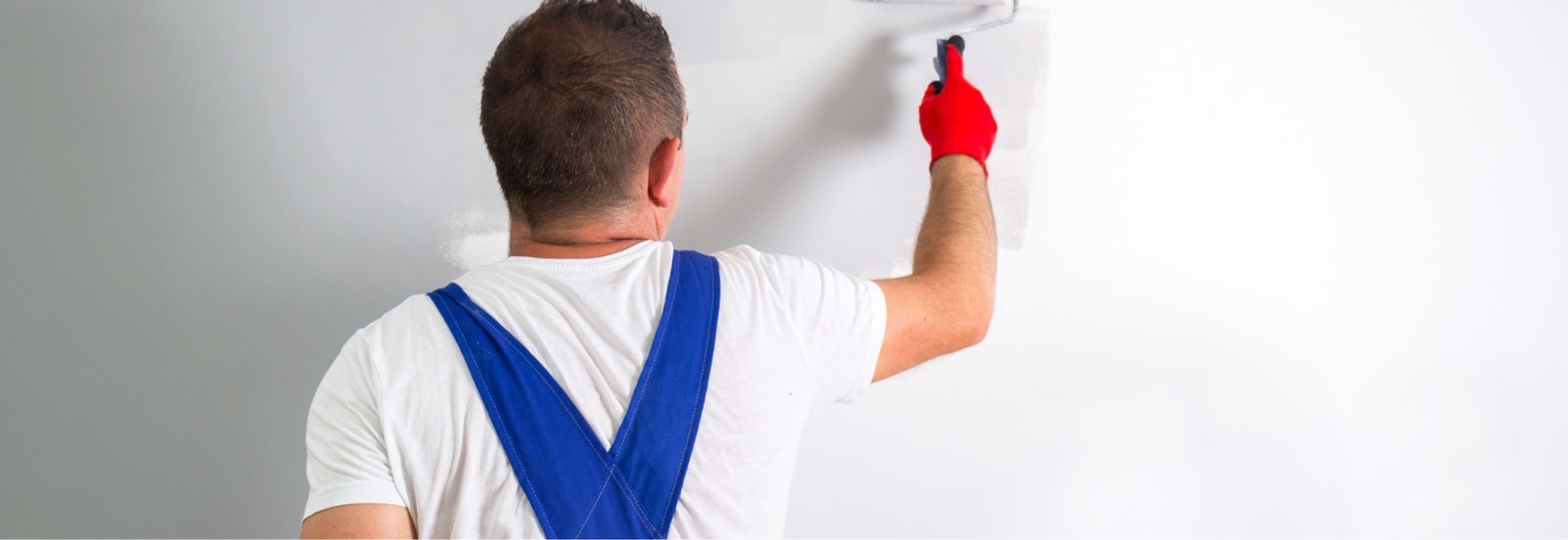 Hombre pintando con rodillo una pared en blanco